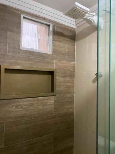 a bathroom with a glass shower with a window at Condomínio manguezal, Apartamento 07 in Porto De Galinhas