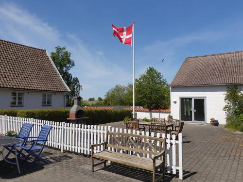 a kite flying over a white fence with chairs and a table at Feriestedet Skovly in Klemensker