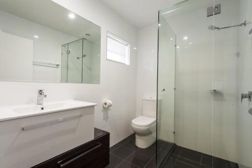 a bathroom with a toilet and a glass shower at Abbey Motor Inn in Grafton