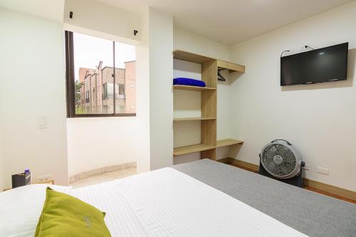 a bedroom with a bed and a tv on the wall at Hotel Balcones del Estadio in Medellín