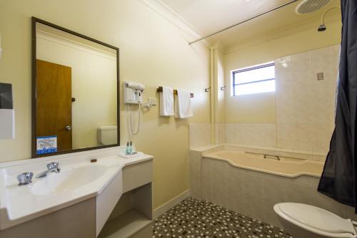 a bathroom with a sink and a tub and a toilet at Abbey Motor Inn in Grafton
