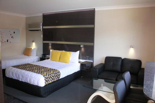 a hotel room with a bed and a chair at Abbey Motor Inn in Grafton