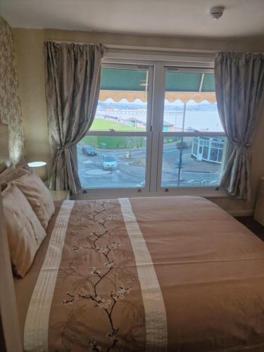 a bedroom with a large bed and a large window at The Sands Hotel in Paignton