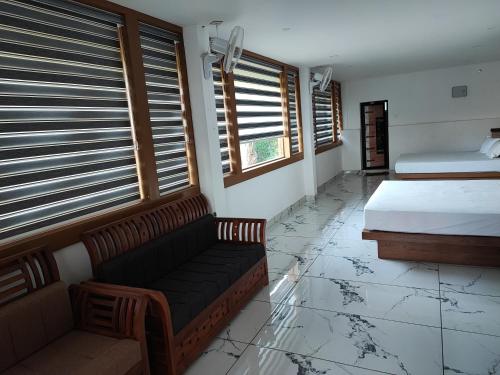 a bedroom with a couch and a bed and windows at Green Garden Wayanad Villas in Vayittiri