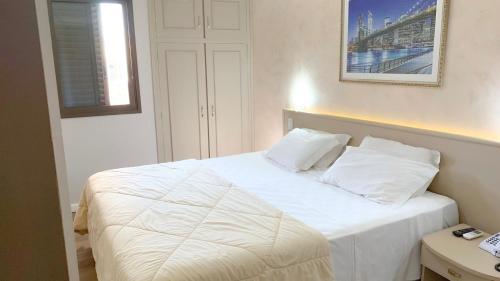 a bedroom with a bed with white sheets and pillows at Hotel Pousada da Serra in Maracaju