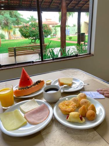 a table with plates of food on a table at Hotel Pousada da Serra in Maracaju