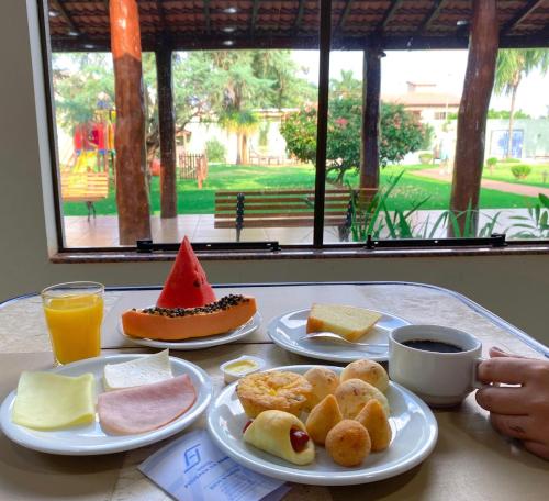 a table with two plates of food and a cup of coffee at Hotel Pousada da Serra in Maracaju