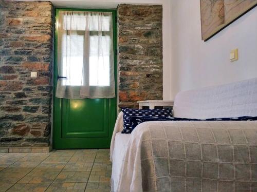 a green door in a room with a bed at Zenios Andros-Cycladic house overlooking Batsi bay in Batsi