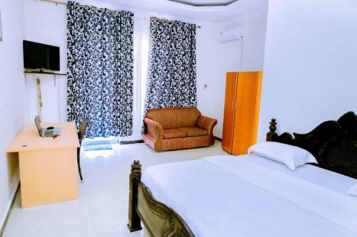 um quarto com uma cama, uma cadeira e uma televisão em Lao Tangren Guest House em Kigali
