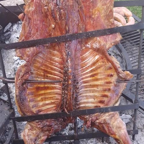 a large piece of meat cooking on a grill at Hotel Lago del Desierto in El Chalten