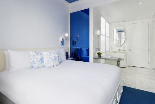 a white bedroom with a large bed and a bathroom at NoMo SoHo in New York