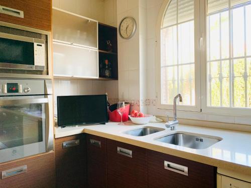 a kitchen with a sink and a clock on the wall at VILLA CIUDAD GOLF PLAYA MONTAÑA in Otura