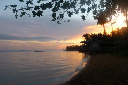 a house on the shore of a lake at sunset at Serenity Resort Koh Chang in Ko Chang