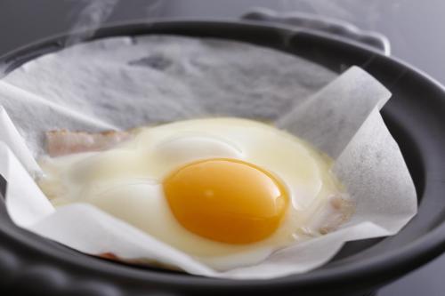 a fried egg in a black pan with paper at Oyado Hachibei in Takayama