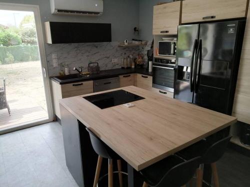 Il comprend une cuisine équipée d'un comptoir en bois et d'un réfrigérateur. dans l'établissement Maison au calme, à Belin-Beliet