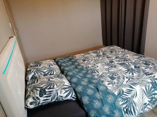 uma pequena cama com um edredão azul e branco em Maison au calme em Belin-Beliet
