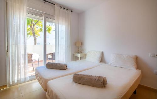 two beds in a white room with a window at Awesome Apartment In Alhama De Murcia With 3 Bedrooms, Wifi And Outdoor Swimming Pool in El Romero