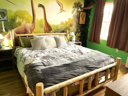 een slaapkamer met een bed met een muurschildering van dinosaurussen bij Jurassic Dino Suite Jiminy-Must See Sleeps 4 in Hancock