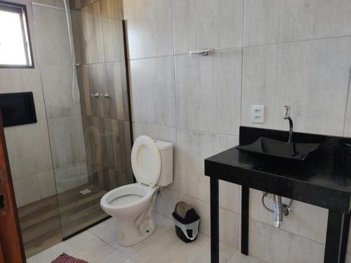 een badkamer met een toilet, een douche en een wastafel bij Hostel Pousada Casa da Praia in Passo de Torres