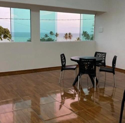 una mesa y sillas en una habitación con ventanas en Sol e mar suítes maragogi, en Maragogi