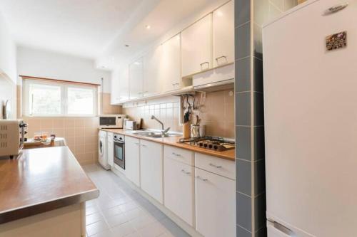 a kitchen with white cabinets and a counter top at Cosy apartment with terrace in Alcabideche
