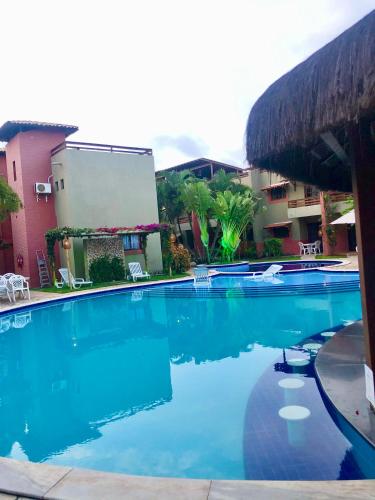 a large blue swimming pool in front of a building at Resort Pipa Casa20 - Triplex maravilhoso in Pipa