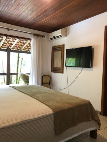 a bedroom with a bed and a flat screen tv on the wall at Sítio Bagatelle com cachoeira e piscina! in Angra dos Reis