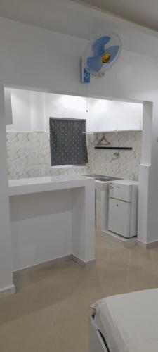 a white kitchen with a white counter top and a stove at Studio NDOUR Castors in Dakar