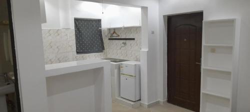 a kitchen with white cabinets and a black door at Studio NDOUR Castors in Dakar