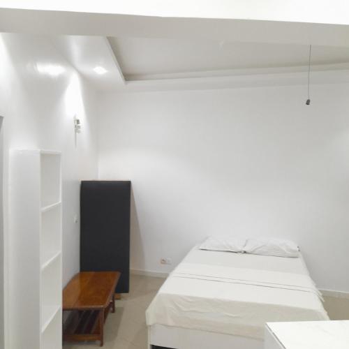 a white room with two beds and a table at Studio NDOUR Castors in Dakar