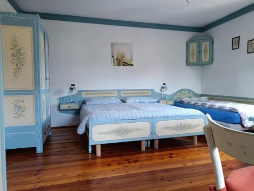 una camera con 2 letti, pareti blu e pavimenti in legno di Dolomia a Villagrande