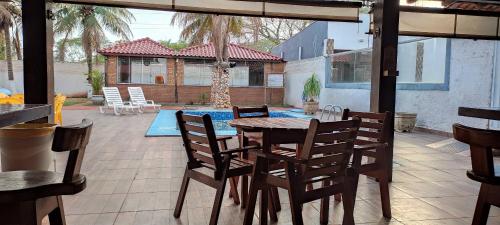 a patio with a table and chairs and a pool at Pousada Capitão Leno in Miranda