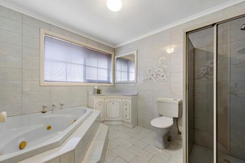 a white bathroom with a tub and a toilet at 12 mins to Mel Airport-Good Wood House in St Albans