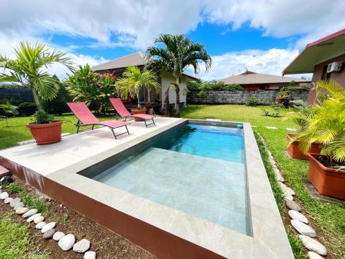 - une piscine avec 2 chaises roses à côté d'une maison dans l'établissement TAHITI - Fare Matavai Piti, à Taravao