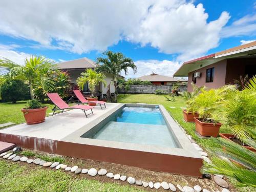a backyard with a swimming pool and two chairs and a house at TAHITI - Fare Matavai Toru in Taravao