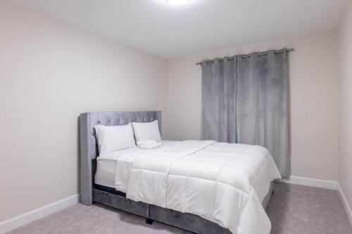 1 dormitorio con 1 cama grande y cabecero gris en Luxury Niagara 3 Bdr Townhouse /Garage, en Niagara Falls