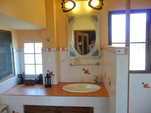 y baño con lavabo y espejo. en Golden Teak Home Resort en Saraphi