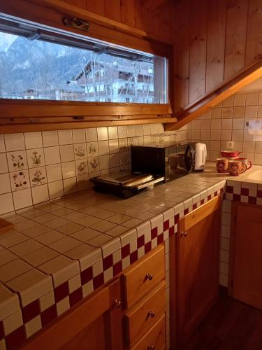 - une cuisine avec un comptoir carrelé et une fenêtre dans l'établissement Deliziosa mansarda con vista Dolomiti, à San Vito di Cadore