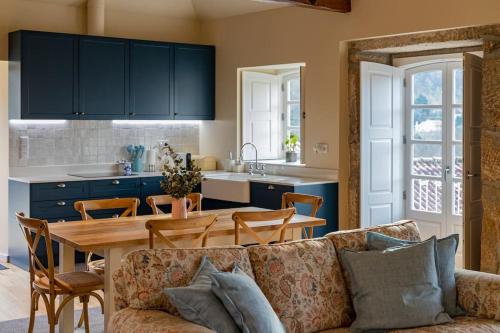 a living room with a couch and a table and a kitchen at Britelo 1828 - Refúgio na Natureza in Ponte da Barca