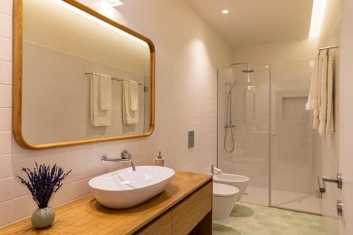y baño con lavabo y ducha con espejo. en Britelo 1828 - Refúgio na Natureza, en Ponte da Barca