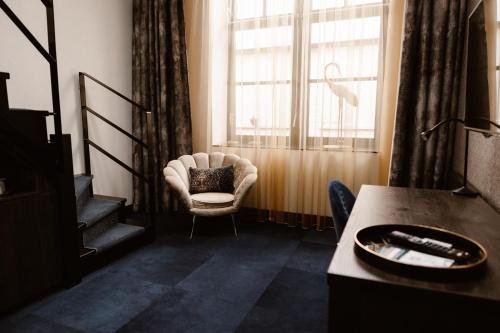 a living room with a chair and a window at Hotel Amerika in Hoek van Holland