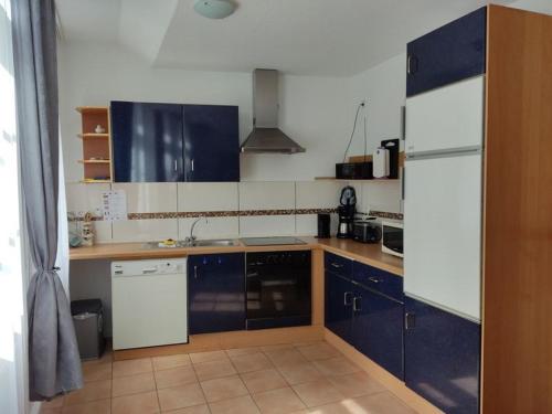 a kitchen with blue cabinets and a white refrigerator at FeWo 1 im ehemaligen Geschenkehaus in Monschau