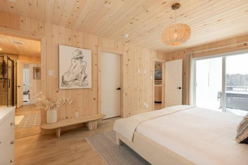 a bedroom with a white bed and a large window at Chalet le Chardonnay - Spa , Foyers , Accès plage Lac-Jaune in Chertsey