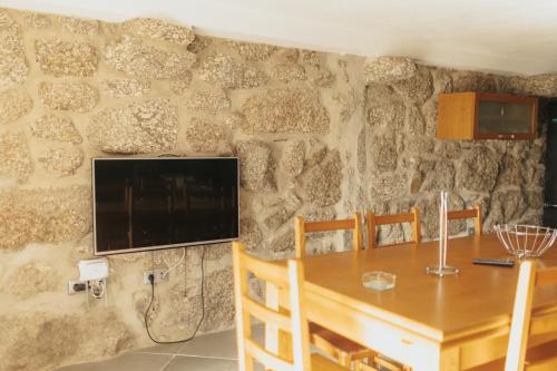 uma sala de jantar com uma mesa e uma televisão numa parede de pedra em Quinta do Rabelo em Braga