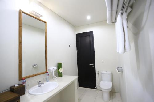 Un baño con lavabo, inodoro y espejo. en Bali Sunset Villa, en Seminyak