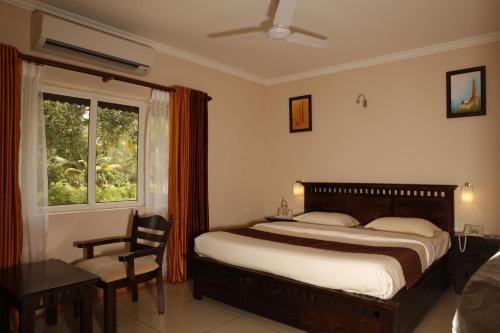 1 dormitorio con cama, escritorio y ventana en Karapuram Village Resort & Spa, en Mararikulam