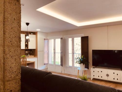 a living room with a couch and a flat screen tv at EL CAPRICHO DEL ARCO_Apartamentos Burgos Catedral in Burgos