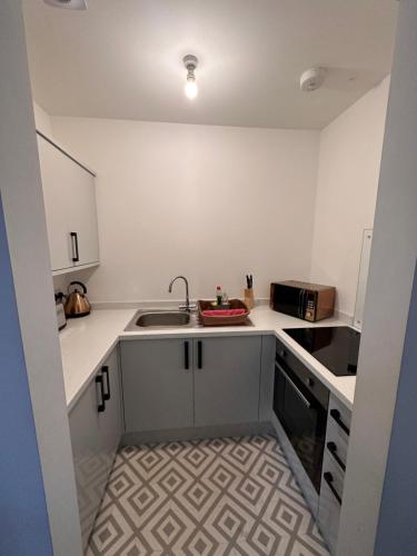 a small kitchen with white cabinets and a sink at City Blessed Aptm 2 with free parking in North Shields
