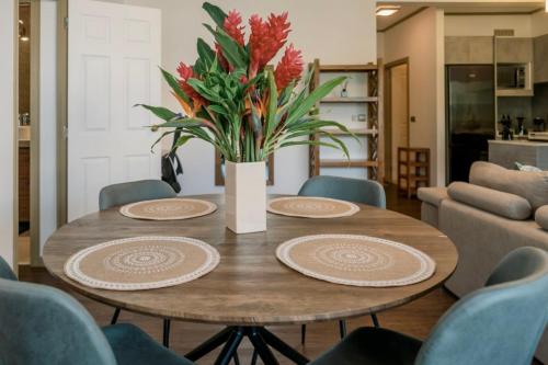 una mesa de comedor con platos y un jarrón de flores en Grand Large - Premium suite, en Papeete