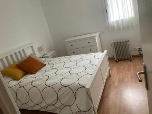 ein weißes Schlafzimmer mit einem Bett mit orangefarbenem Kissen in der Unterkunft Apartamento Edificio Lirios Politur in Platja  d'Aro